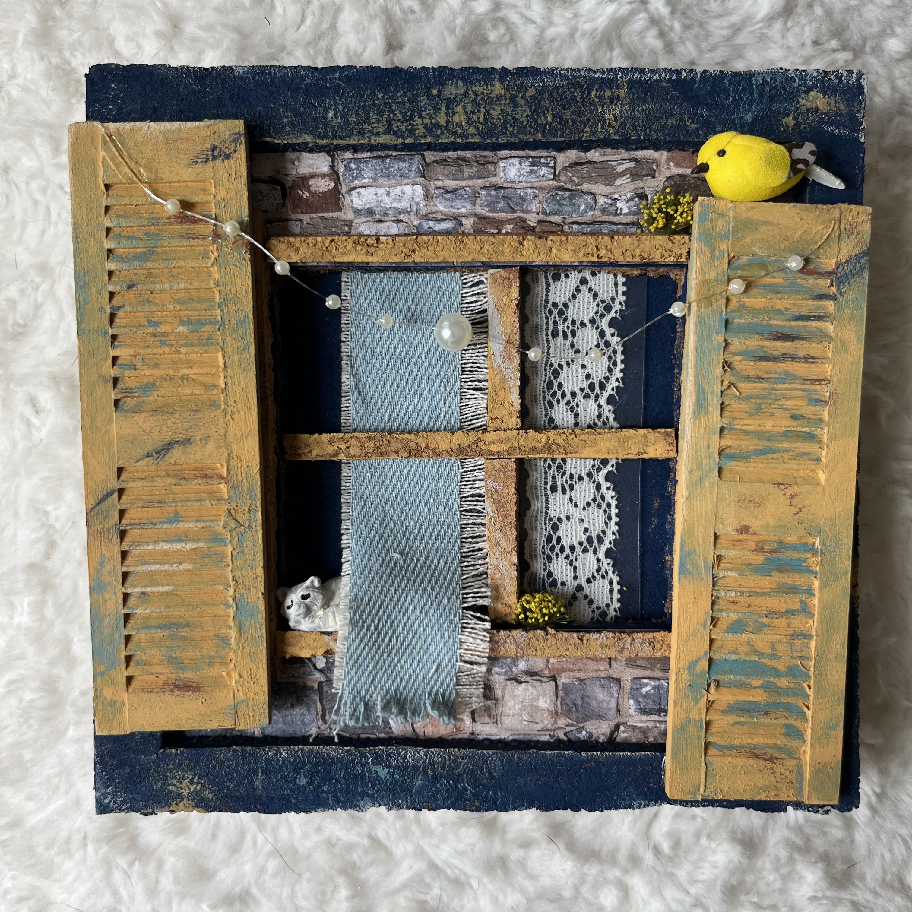 Miniature window scene with sleeping cat, bird, and whimsical faux party lights