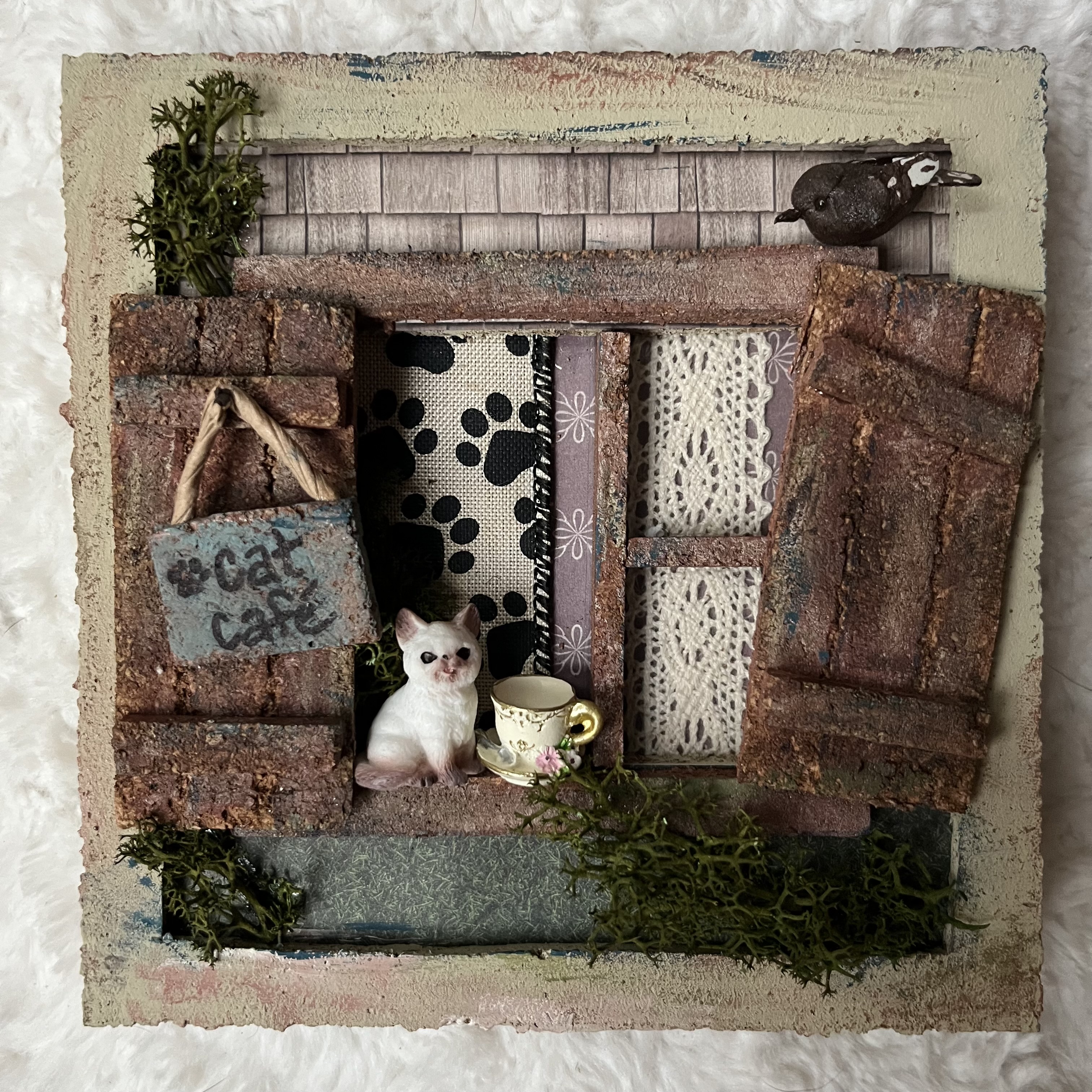 Miniature window scene with cat cafe sign, bird, and dainty tea cup