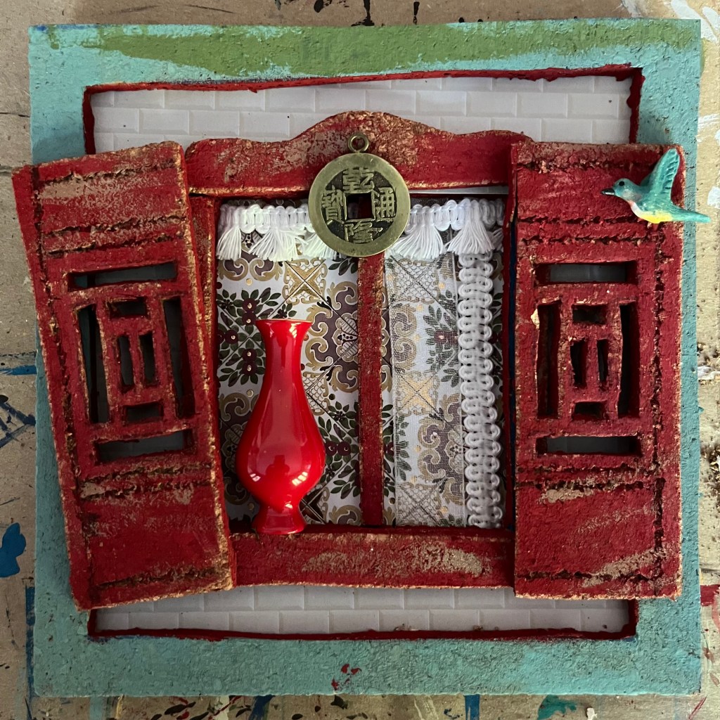 Miniature window scene featuring handcrafted shutters with ancient Chinese latticework, coin for good luck, and elegant red vase